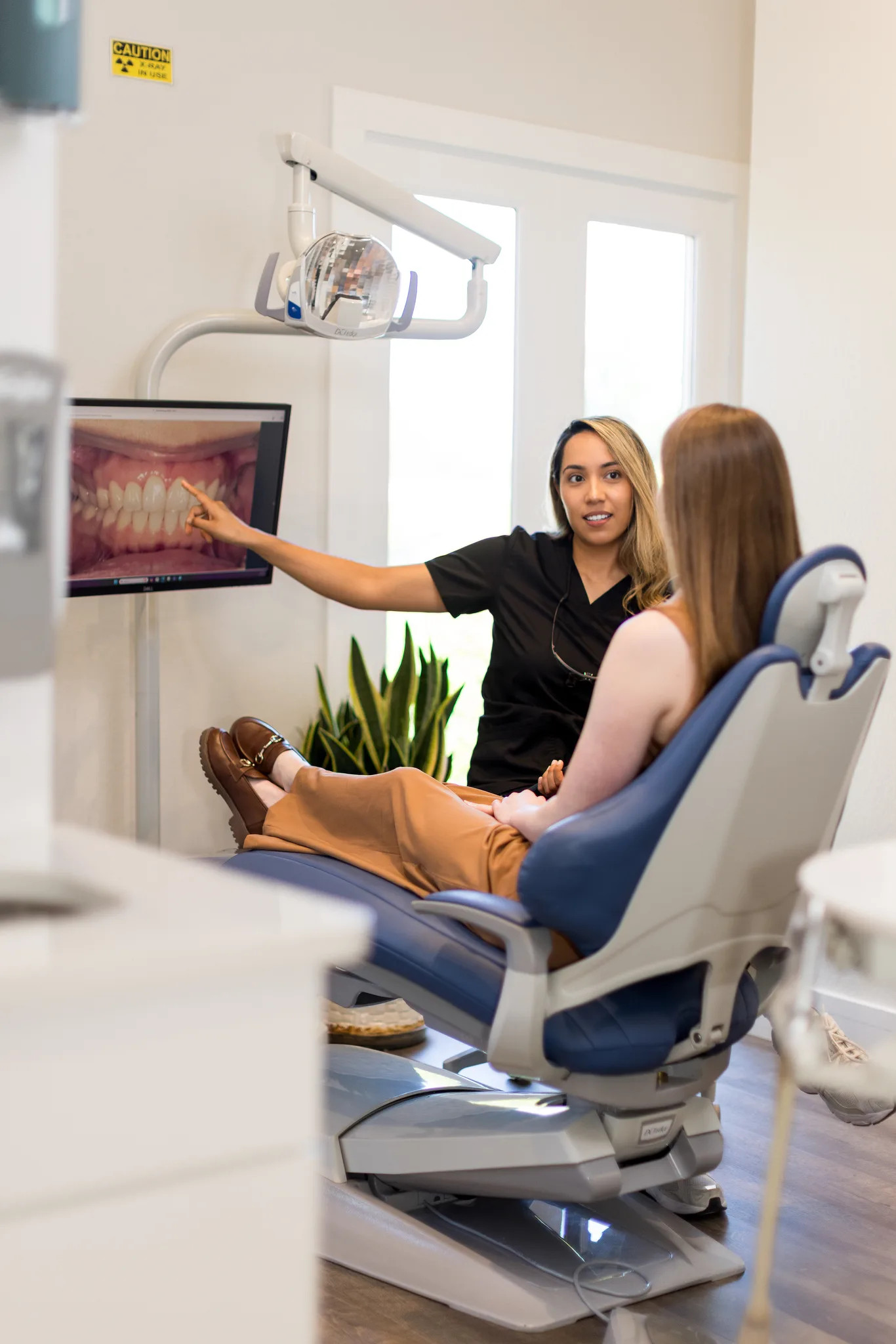 A clinician at Precision Dental Care showing a patient their digital X-rays on a chairside screen