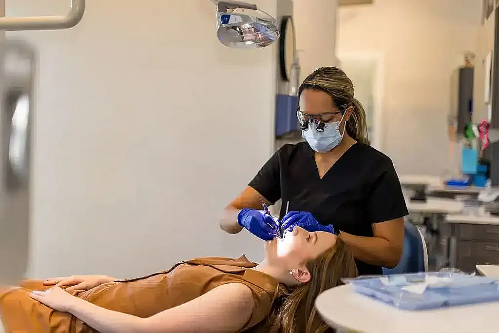 Hygienist cleaning a reclined patient's teeth