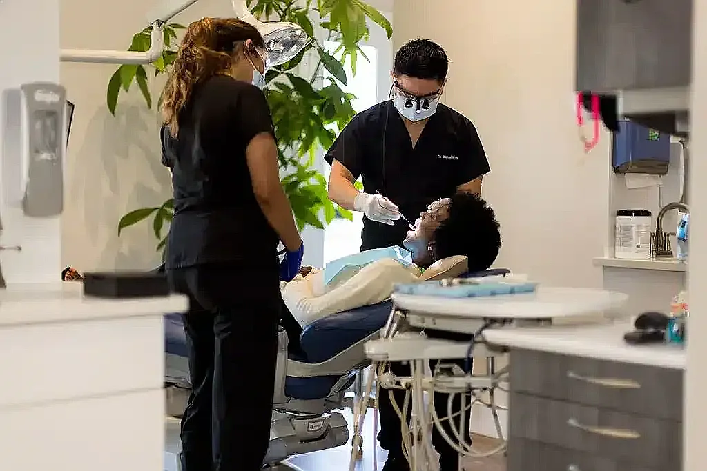 Two clinicians treating a reclined patient during an implant appointment