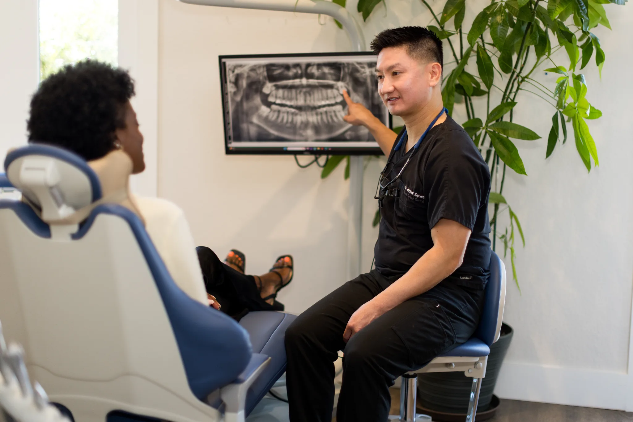 A dentist showing a patient findings on a panoramic X-ray at the chairside