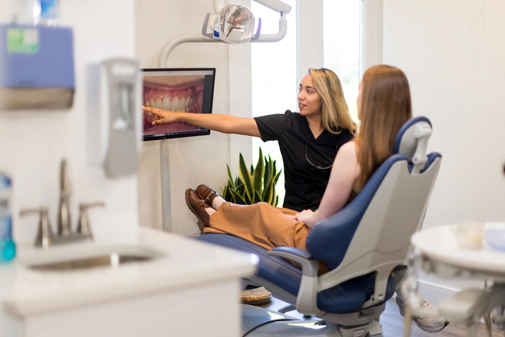 A hygienist pointing out an intraoral photograph of the teeth on the chairside screen