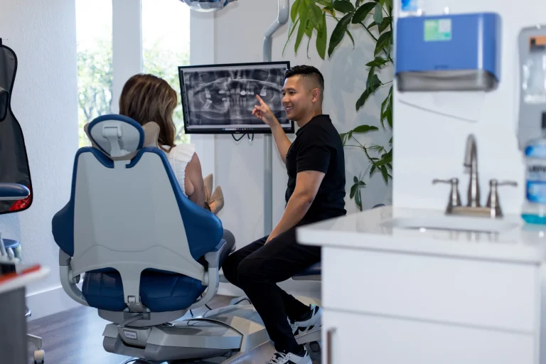 Dr. Nguyen pointing at the treatment plan on the chairside monitor beside a smiling patient