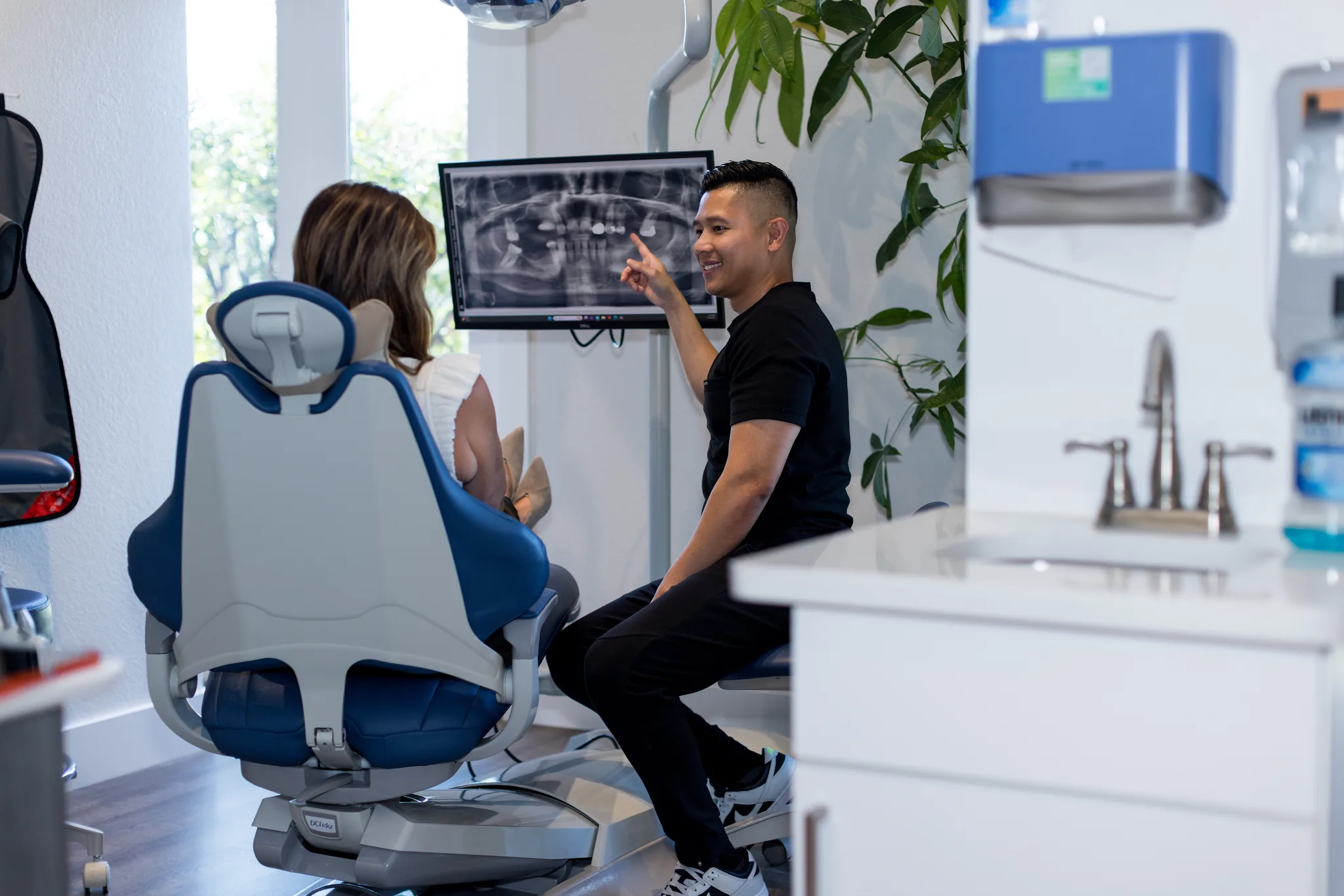 Dr. Nguyen pointing at the treatment plan on the chairside monitor beside a smiling patient