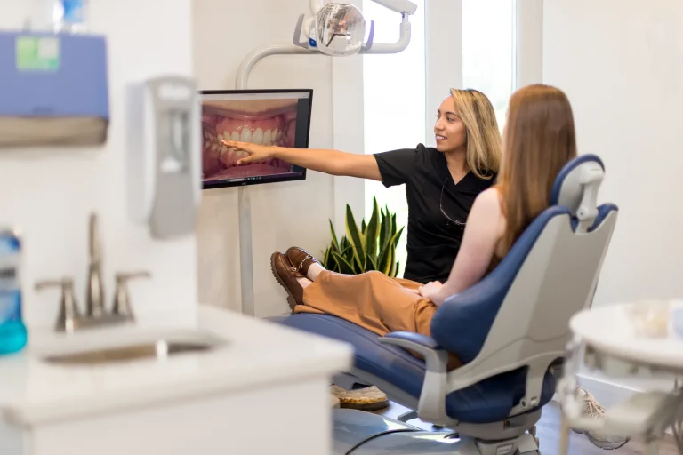 A hygienist pointing out an intraoral photograph of the teeth on the chairside screen