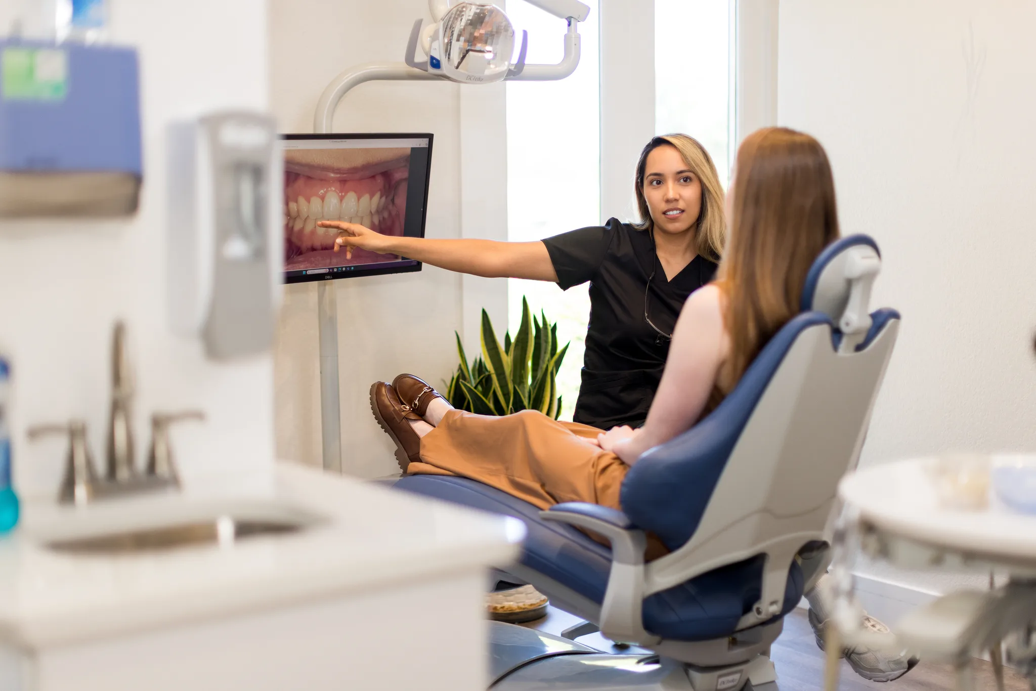 A hygienist pointing out an intraoral photograph of the teeth on the chairside screen