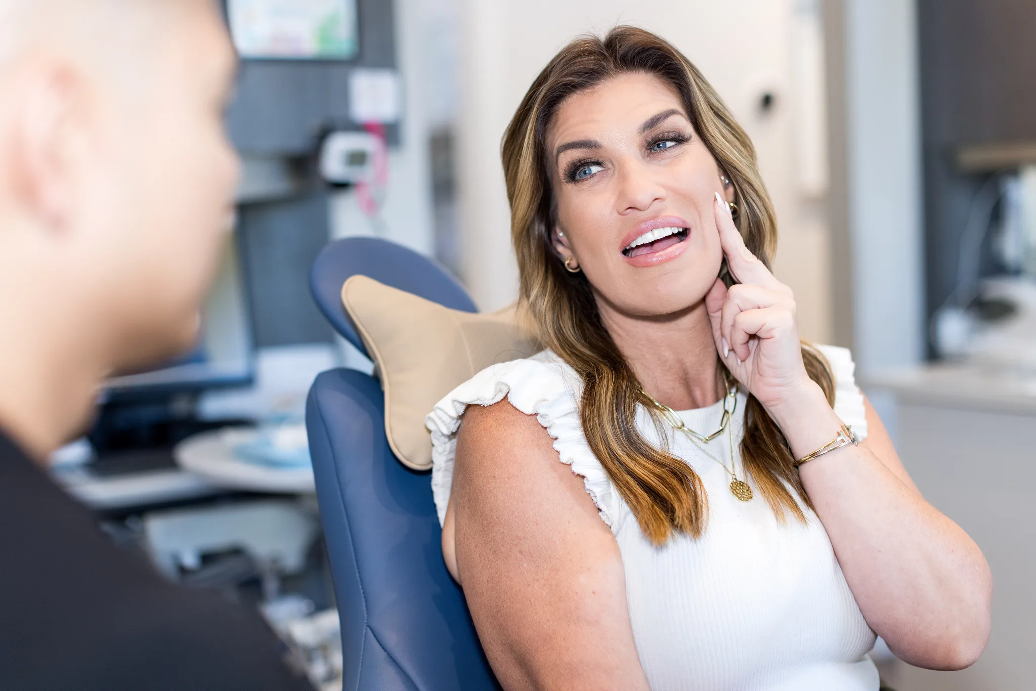 A patient holding her jaw in the dental chair with tooth pain