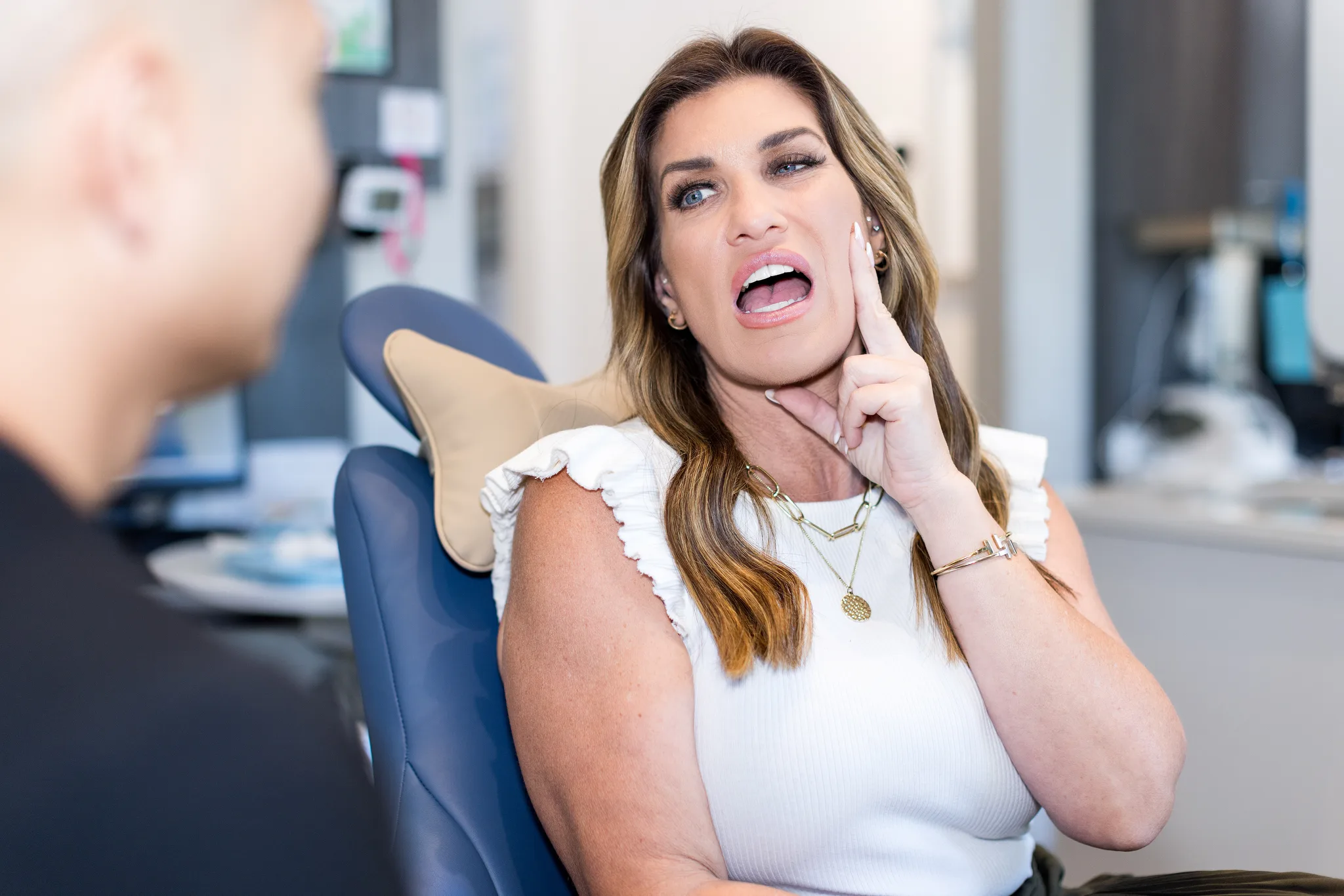 A patient holding her jaw in the dental chair with tooth pain