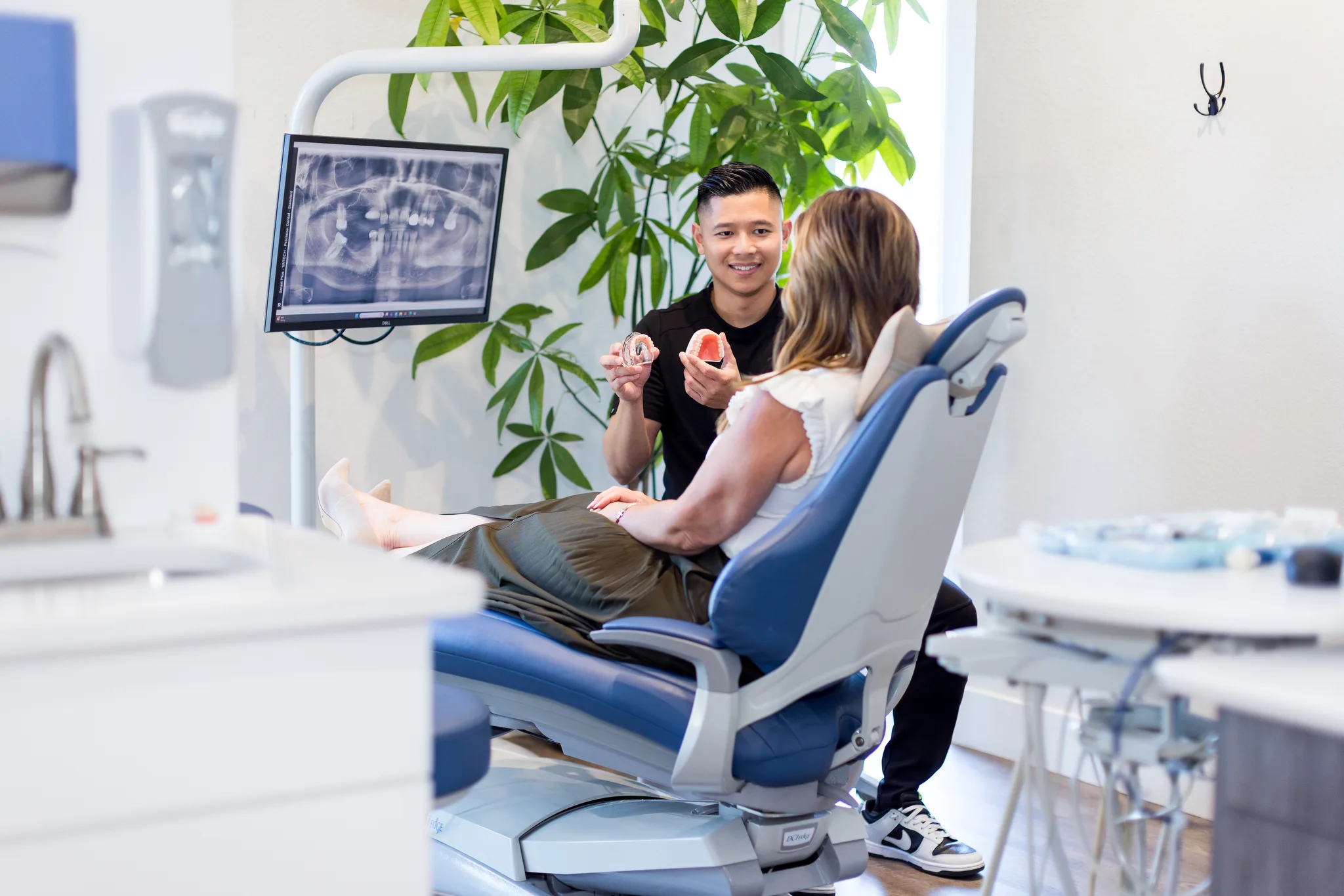 A dentist reviewing a panoramic X-ray with a patient across the operatory