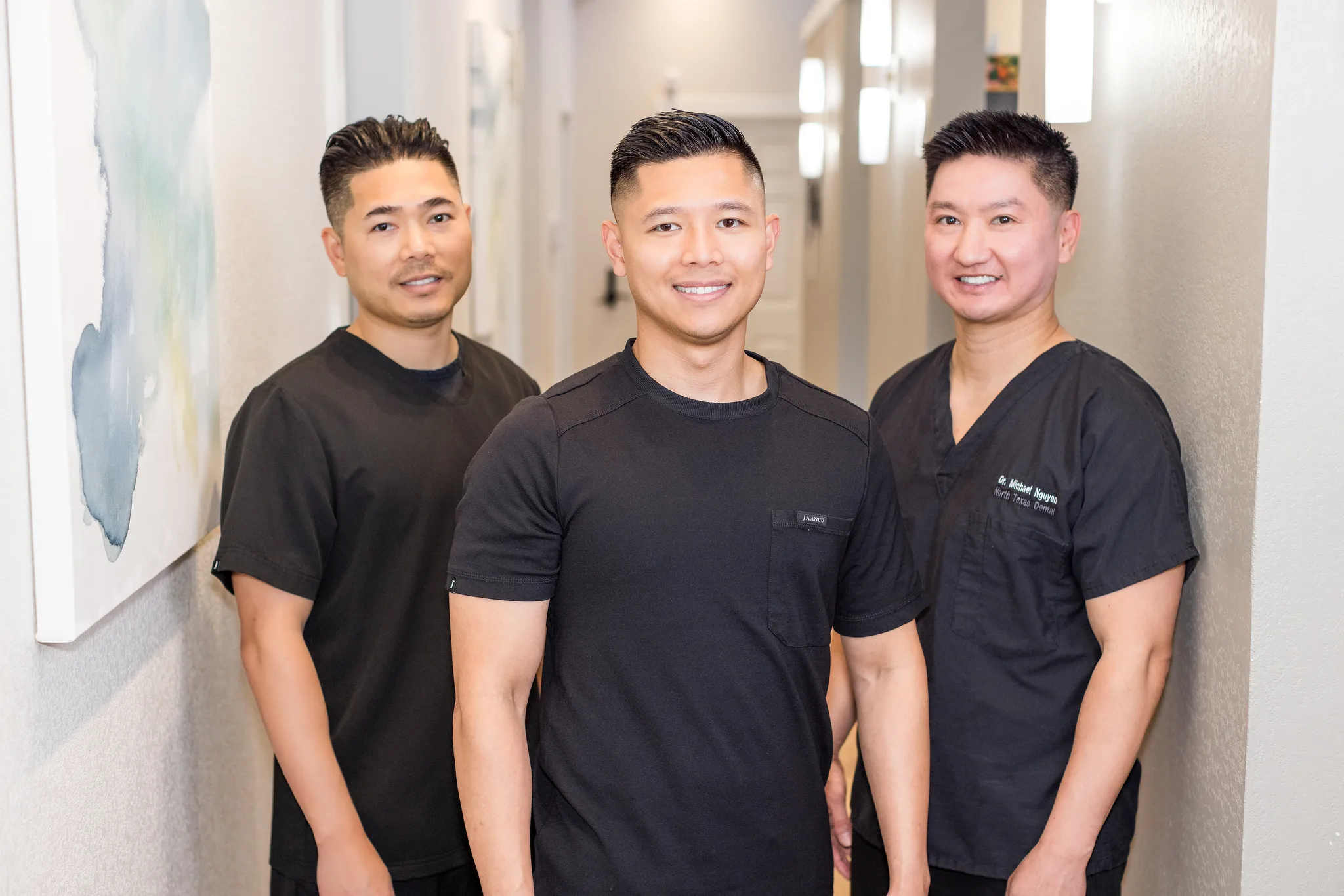 Dentists in black scrubs standing together in the practice hallway