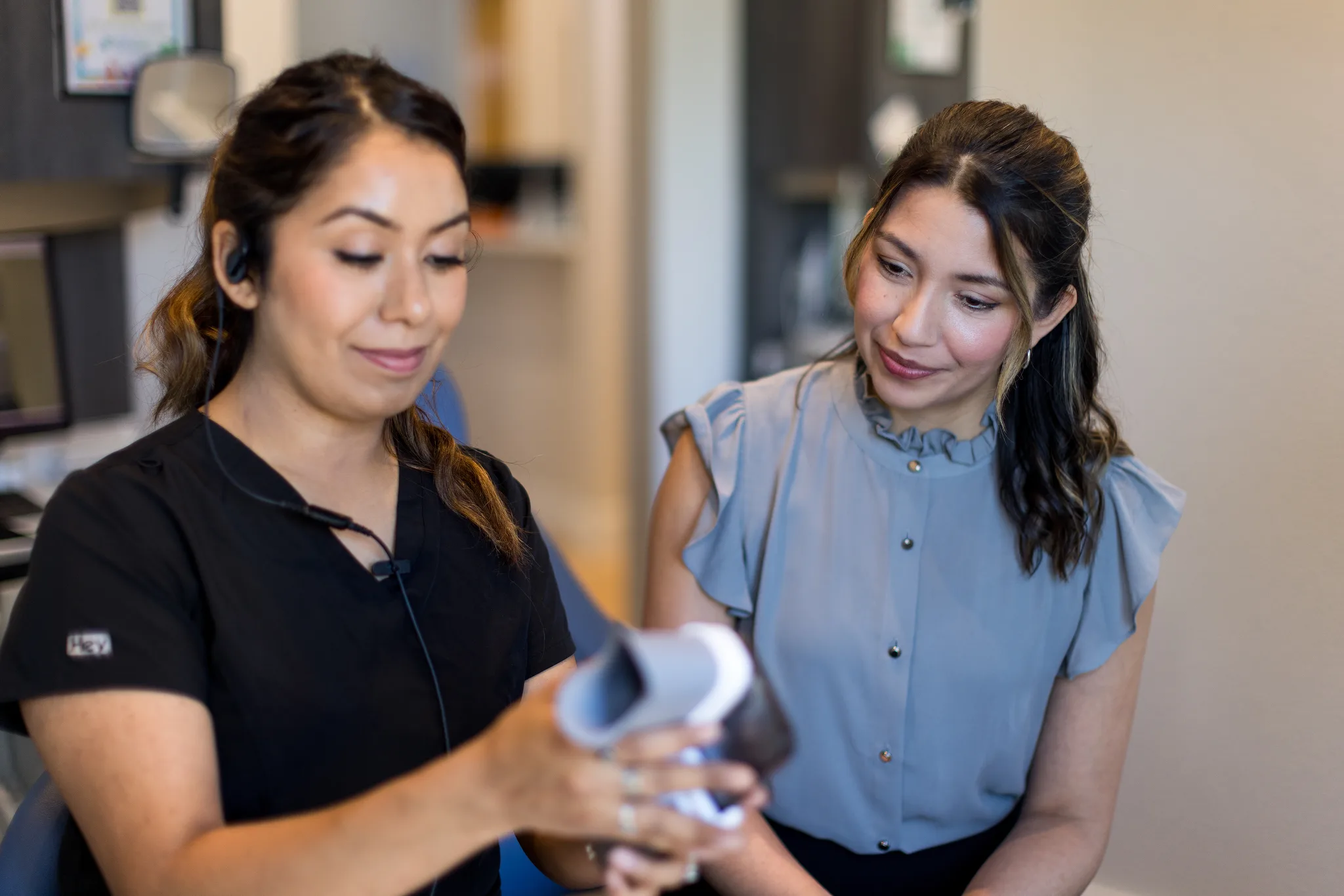 A team member showing a seated patient the intraoral scanner used to take digital impressions