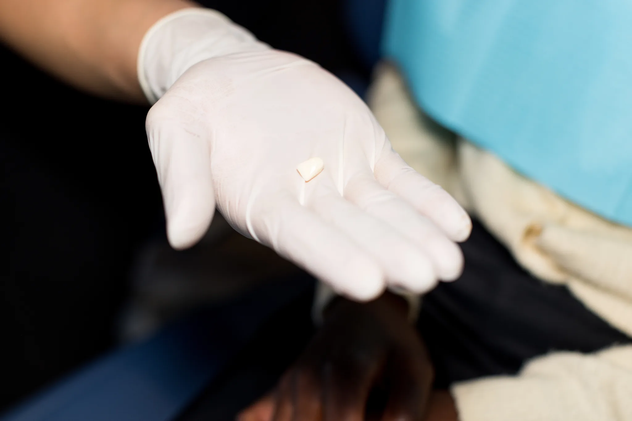 A gloved hand holding a finished restoration on a fingertip