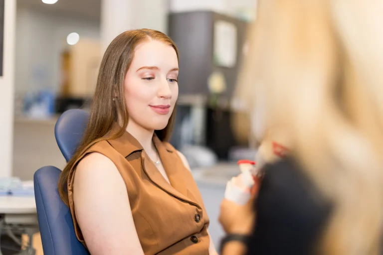 A patient smiling in the chair while talking with her hygienist