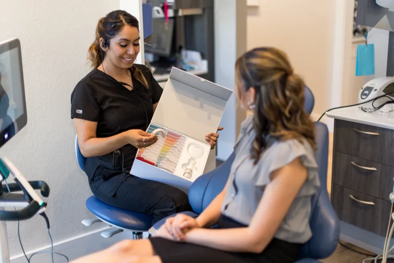A clinician showing a patient a shade guide to plan her whitening result
