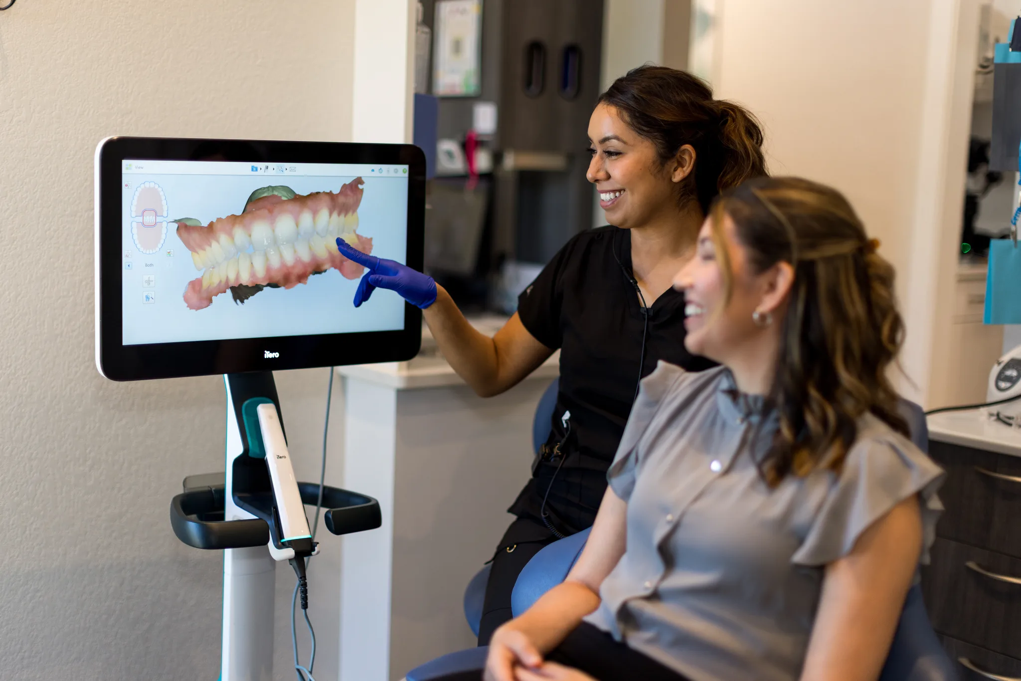 Clinician reviewing a 3D dental scan on a large chairside screen with a patient