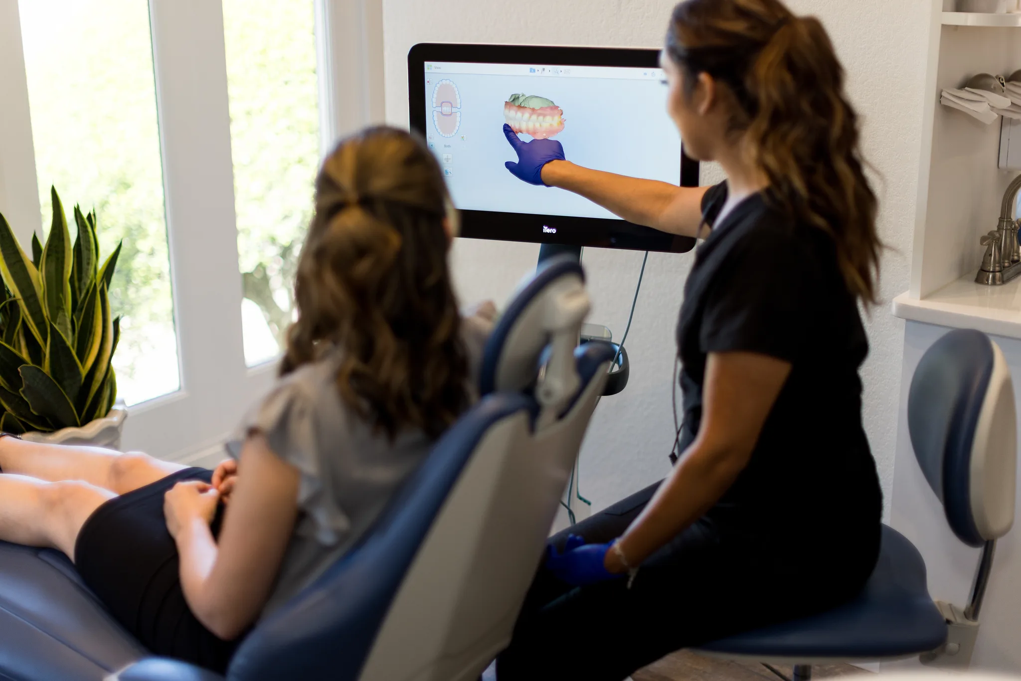 Clinician taking a digital impression with an intraoral scanner, the scan building on screen