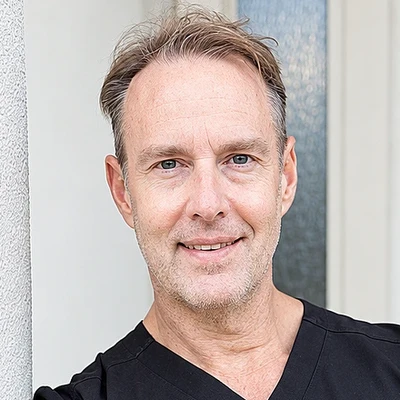 Dr. Tom Draper, smiling, in black scrubs